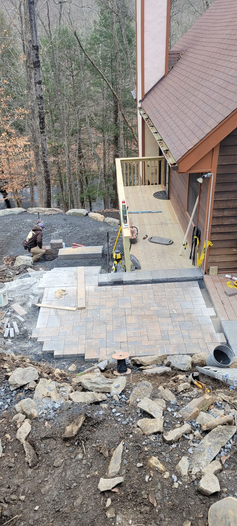 A patio is being built in front of a house in the woods.
