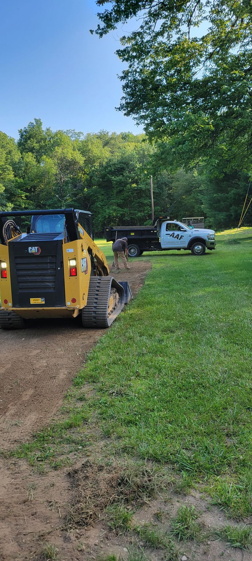 a bulldozer is driving down a dirt road next to a truck .