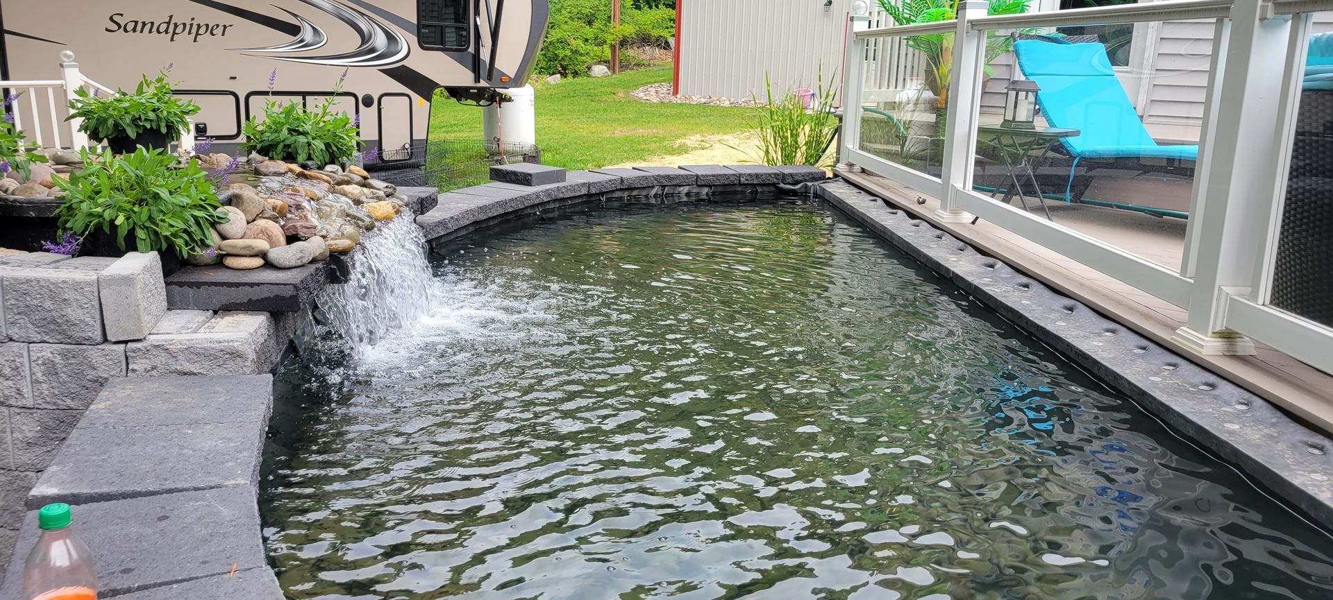 a pond with a waterfall in the middle of it in a backyard .