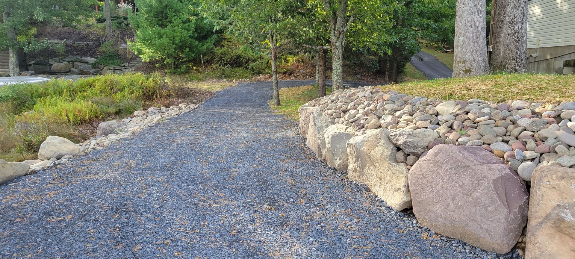 A gravel path surrounded by rocks and trees in a park.