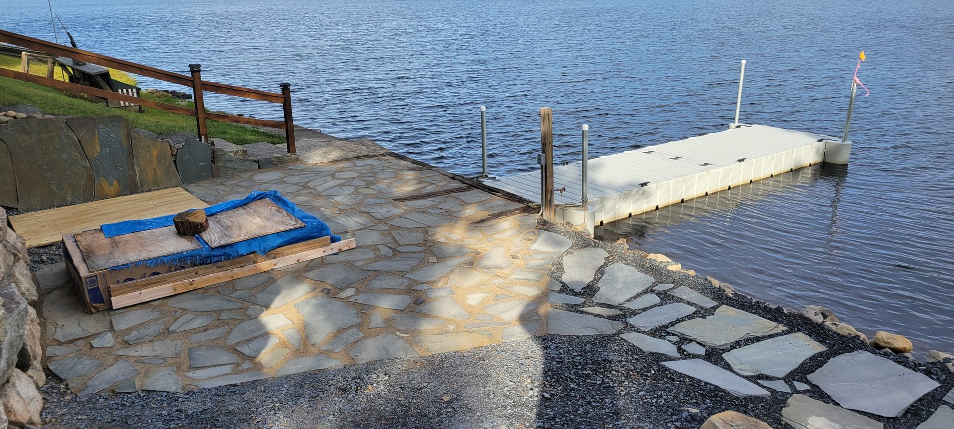 A sandbox is sitting on the shore of a lake next to a dock.