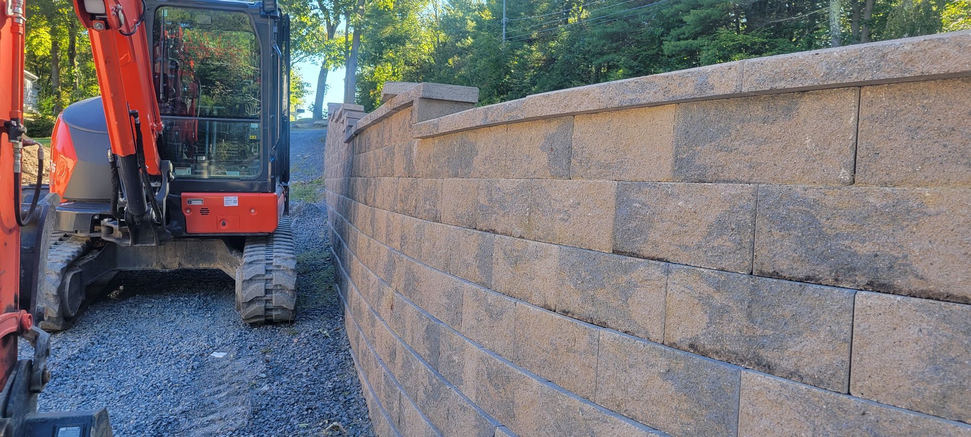 An excavator is sitting next to a brick wall.