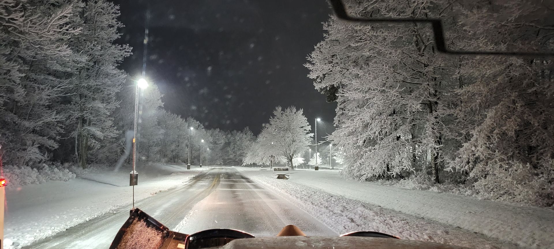 a car is driving down a snowy road at night .