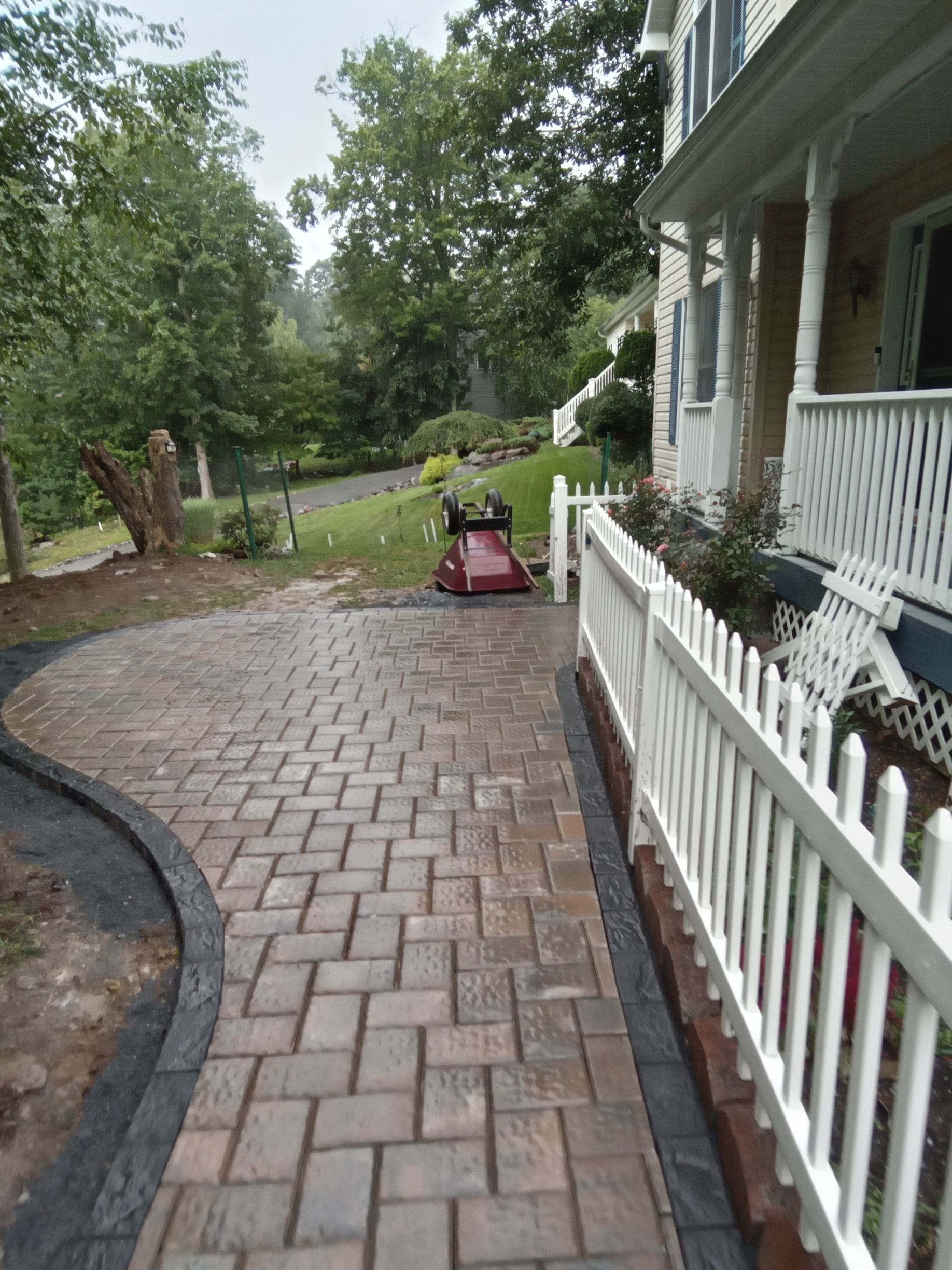 A white railing is being installed on the stairs of a brick house.