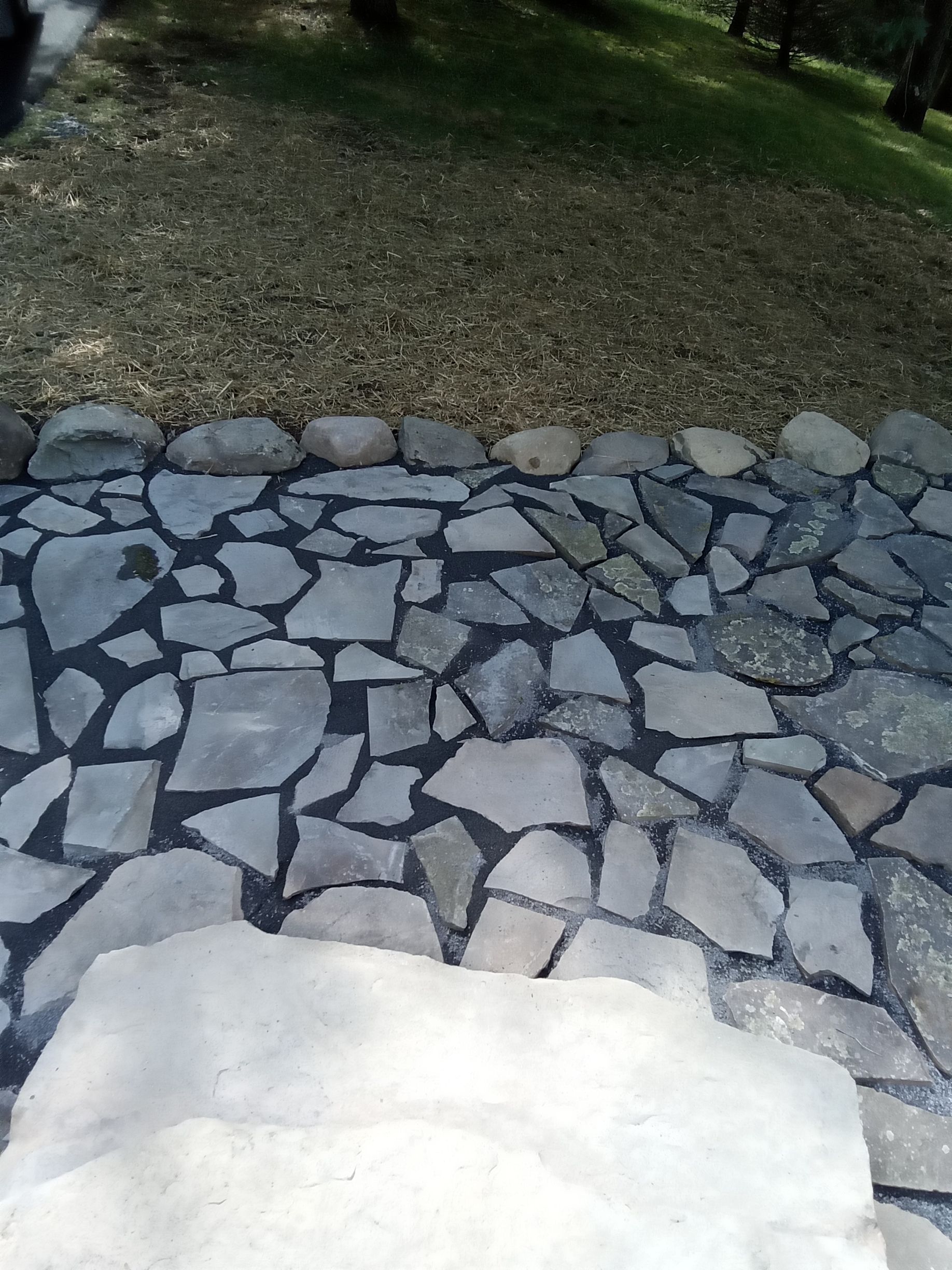 Stone pathway with irregular, gray flagstones leading to grassy area.