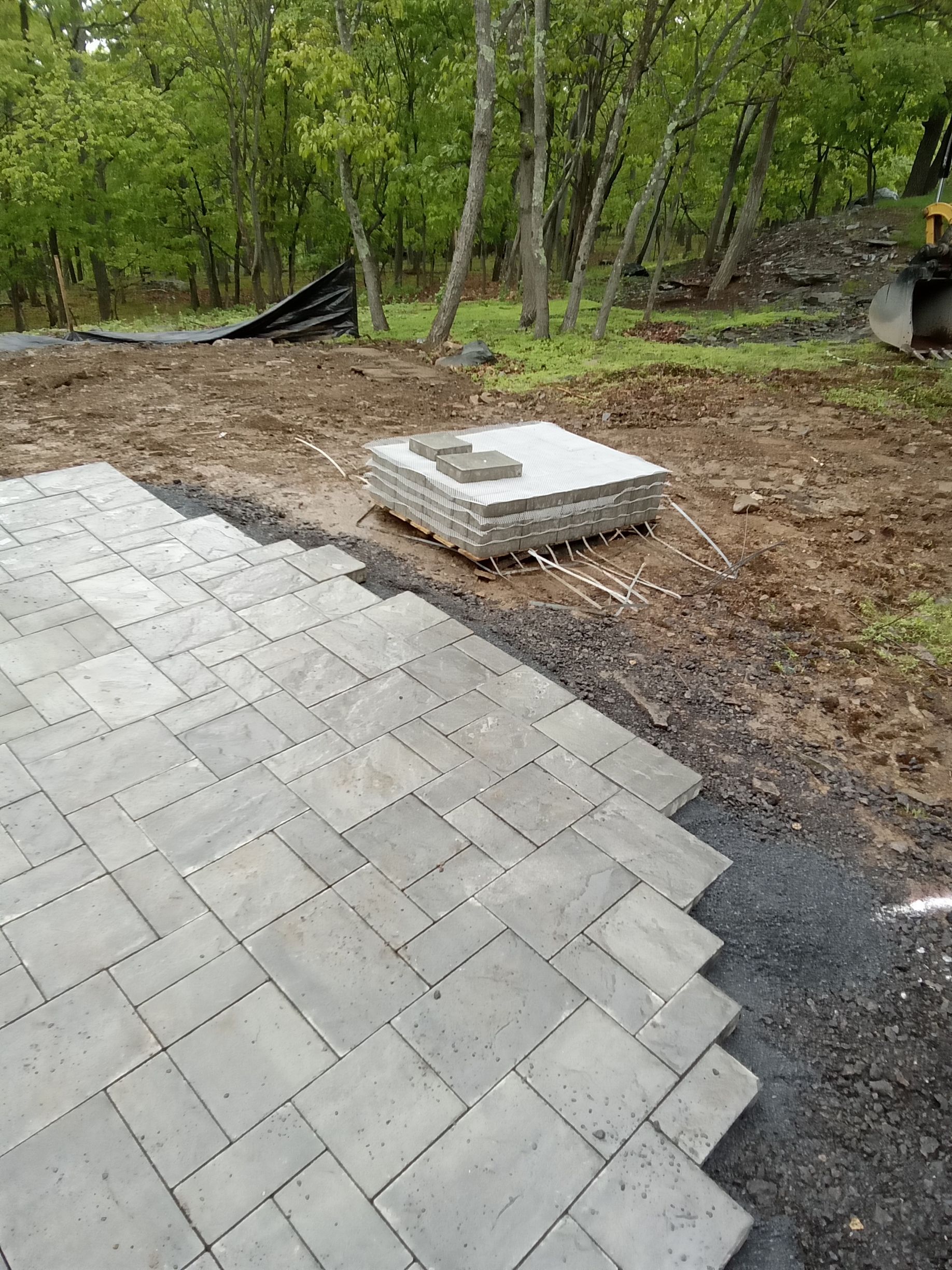 a brick house with a porch and stairs being built by A.A.F Landscaping