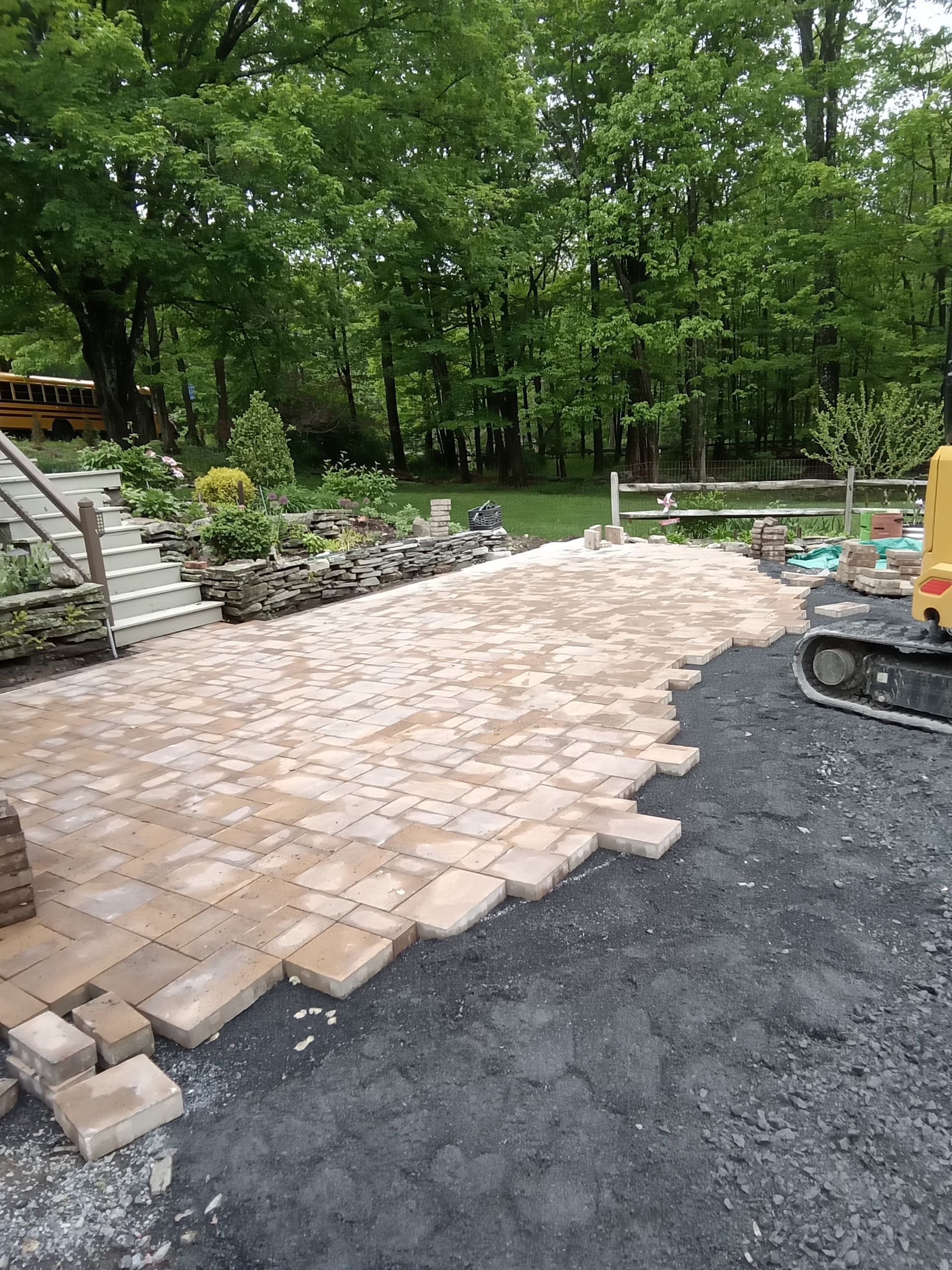a fire pit is being built by A.A.F Landscaping on a patio with bricks laying on the ground .