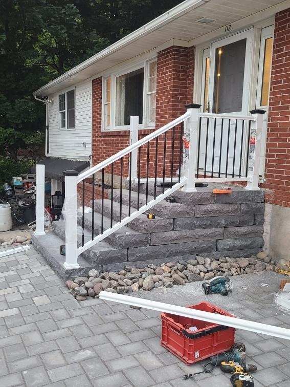 a white railing is being installed on the stairs of a brick house .