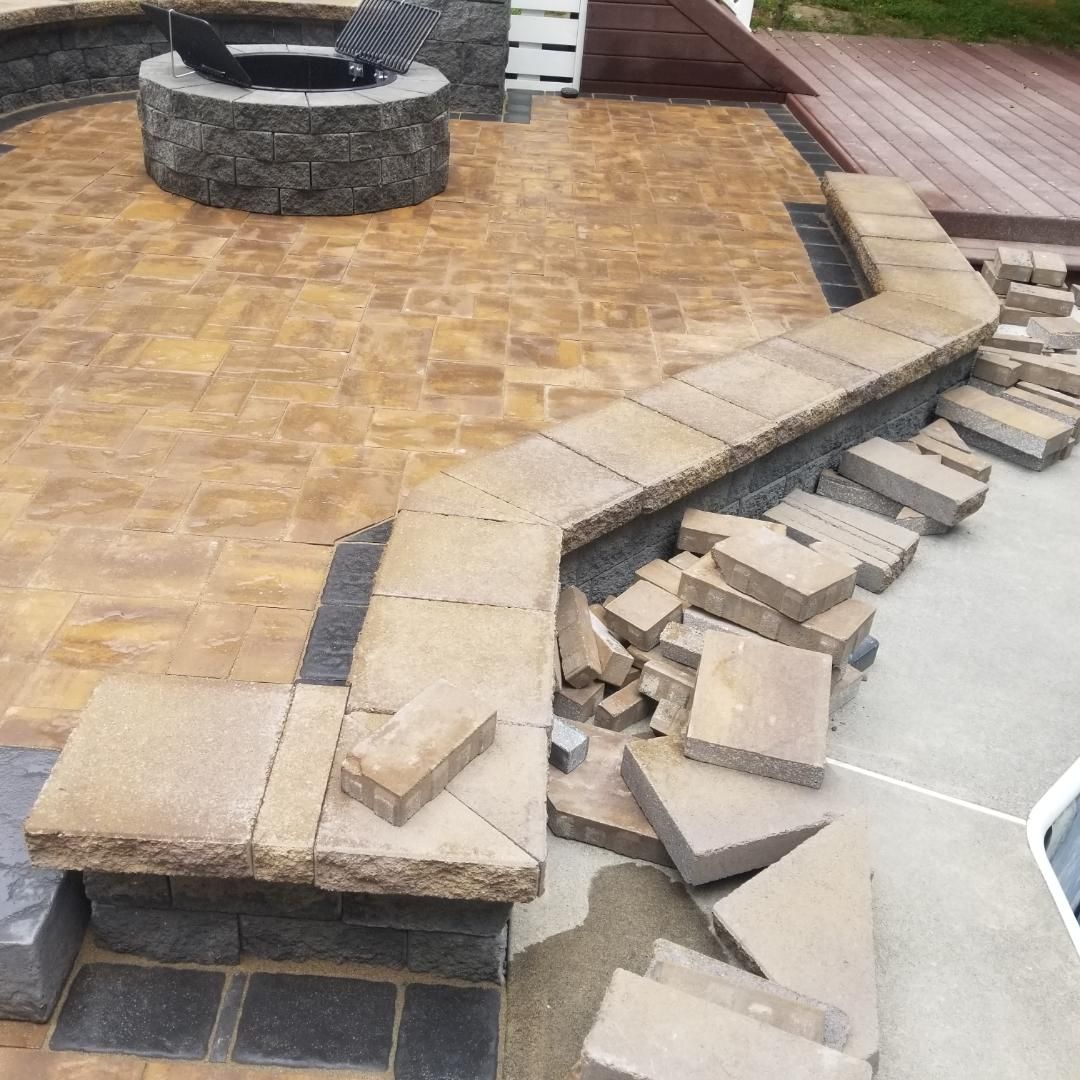 a fire pit by A.A.F Landscaping is being built on a patio with bricks laying on the ground .