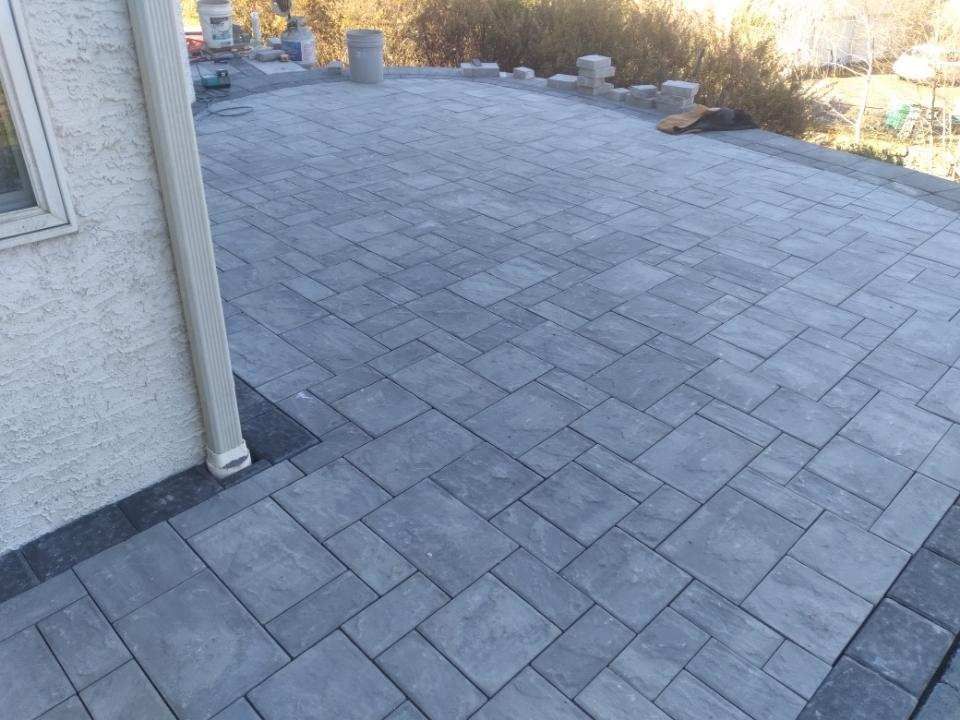 a patio with a black border is being built in front of a house .