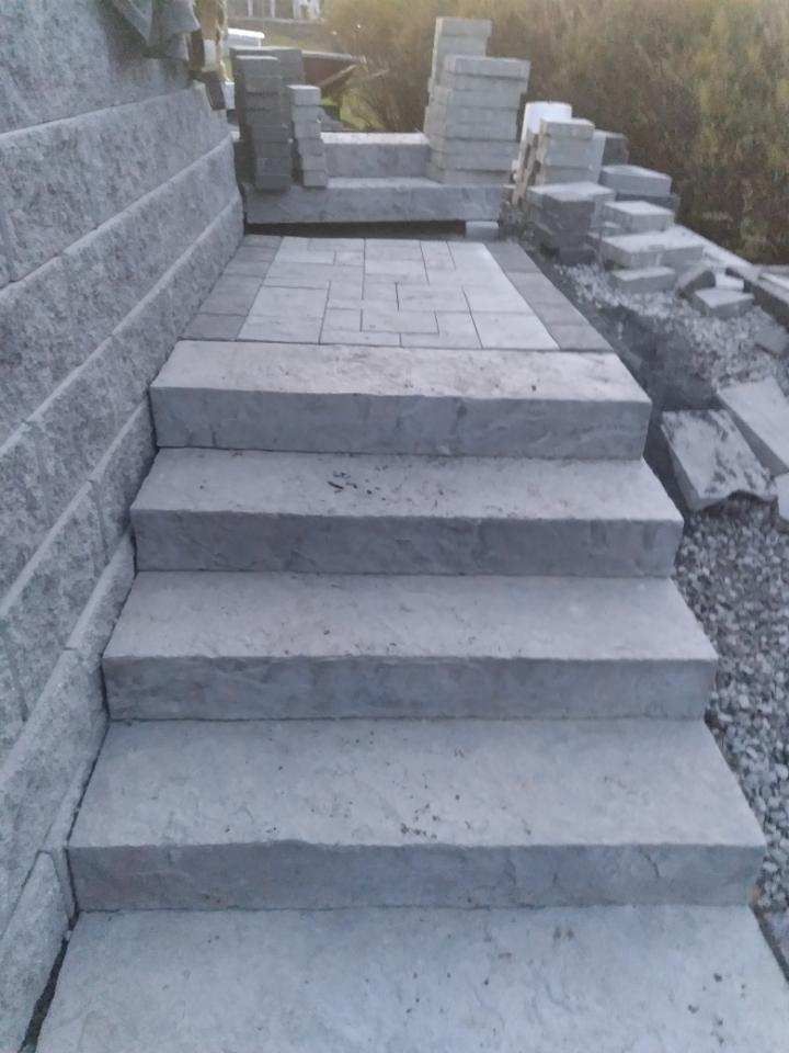 A set of concrete stairs leading up to a brick wall.