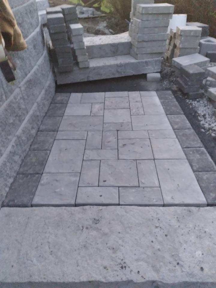 A brick walkway is being built next to a brick wall.