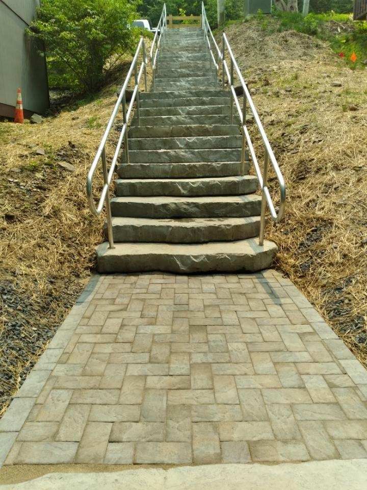 A set of stairs going up a hill with a metal railing