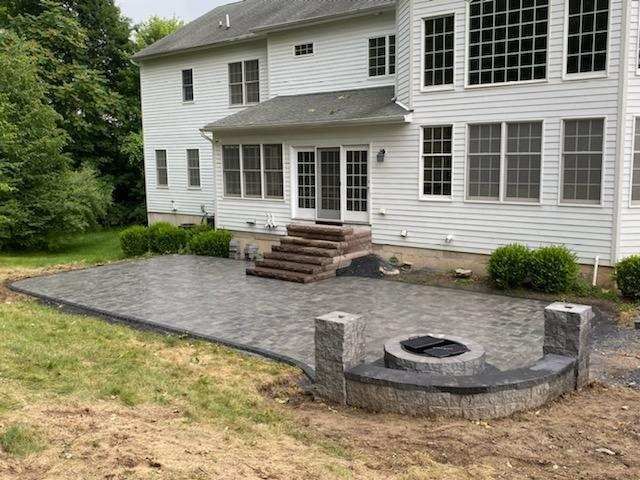 A large white house with a patio and a fire pit in front of it.