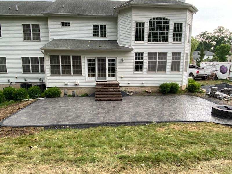 a large white house with a patio in front of it by A.A.F Landscaping