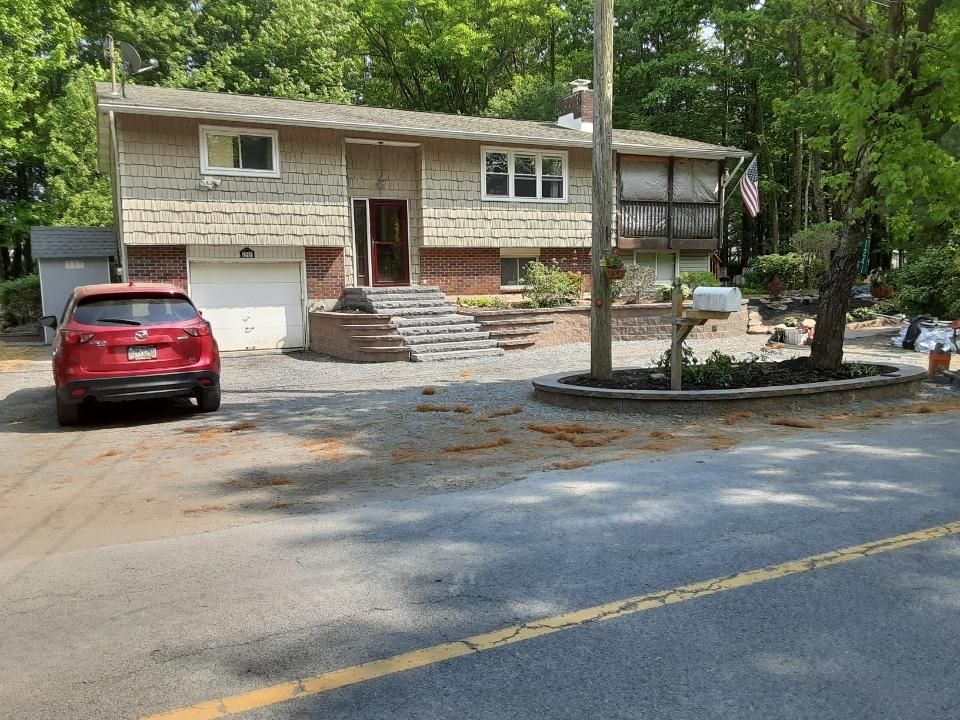a red car is parked in front of a house with hardscaping done by A.A.F Landscaping