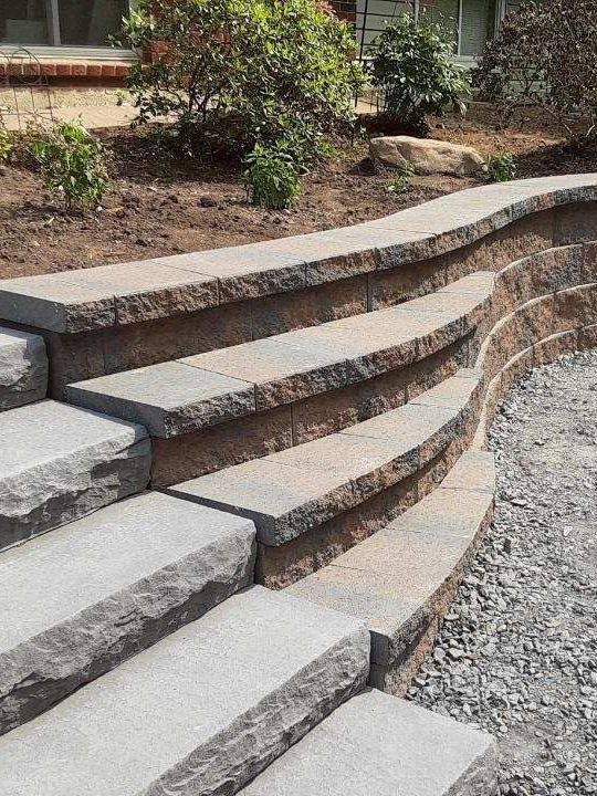 a set of stone stairs next to a stone wall created by A.A.F Landscaping
