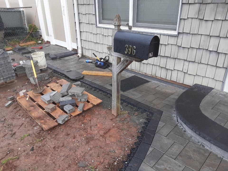 A black mailbox is sitting on a wooden post in front of a house.