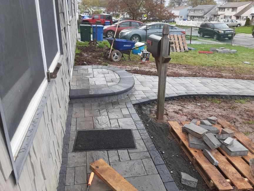 A brick walkway is being built in front of a house.