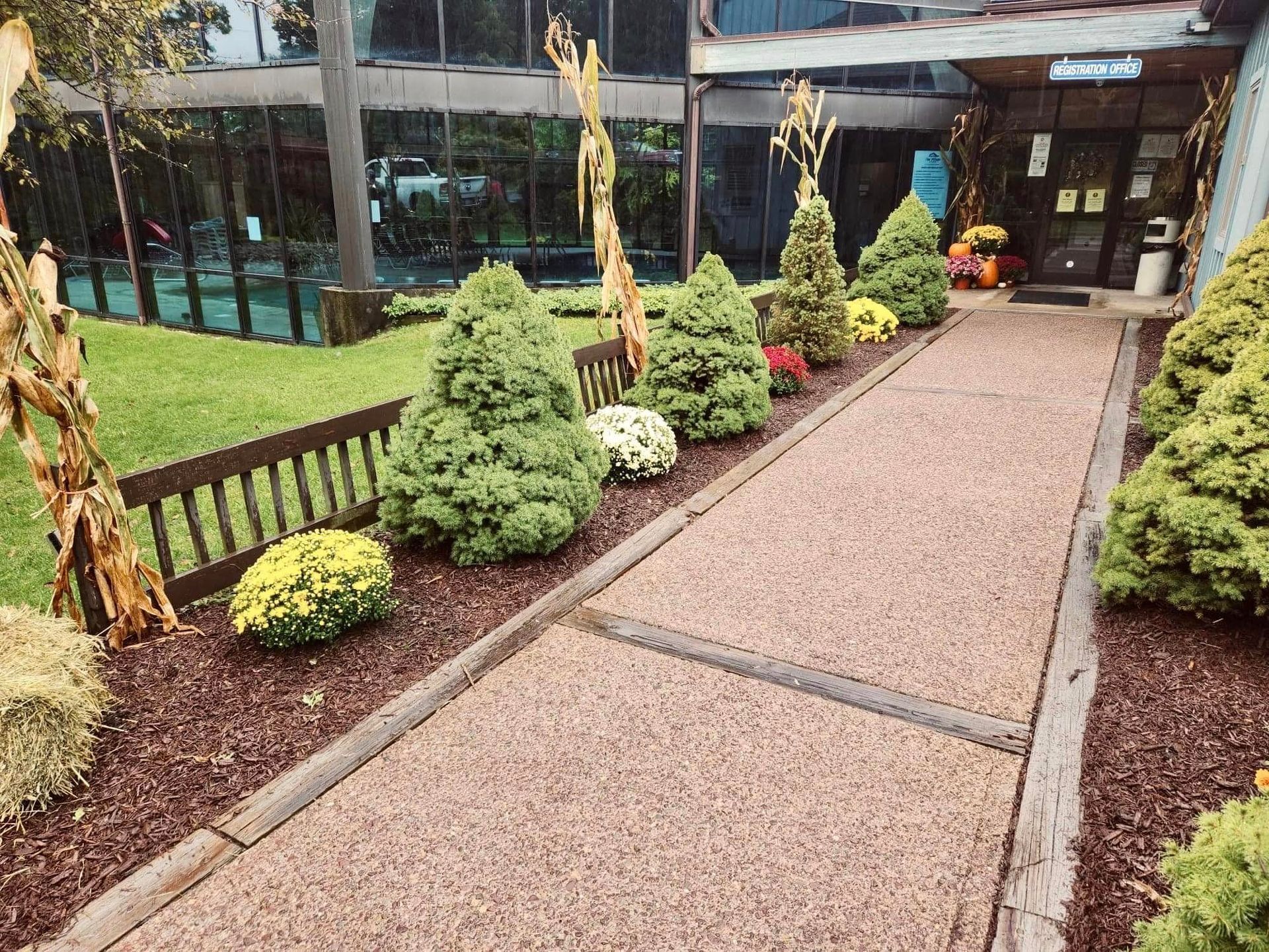 A walkway leading to a building with flowers and trees