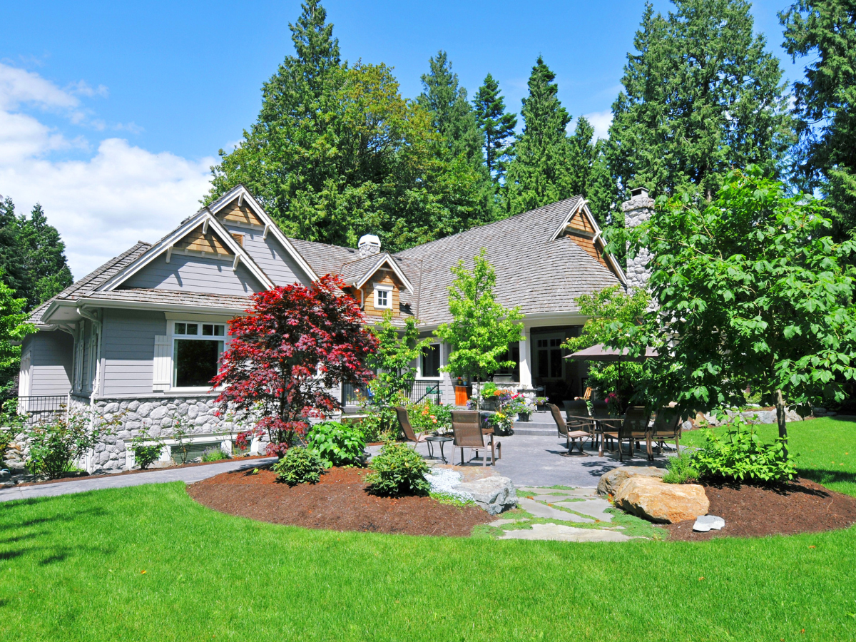 A charming house with gray siding and a stone facade, surrounded by lush green landscaping and a bright blue sky. A charming house with gray siding and a stone facade, surrounded by lush green landscaping and a bright blue sky.