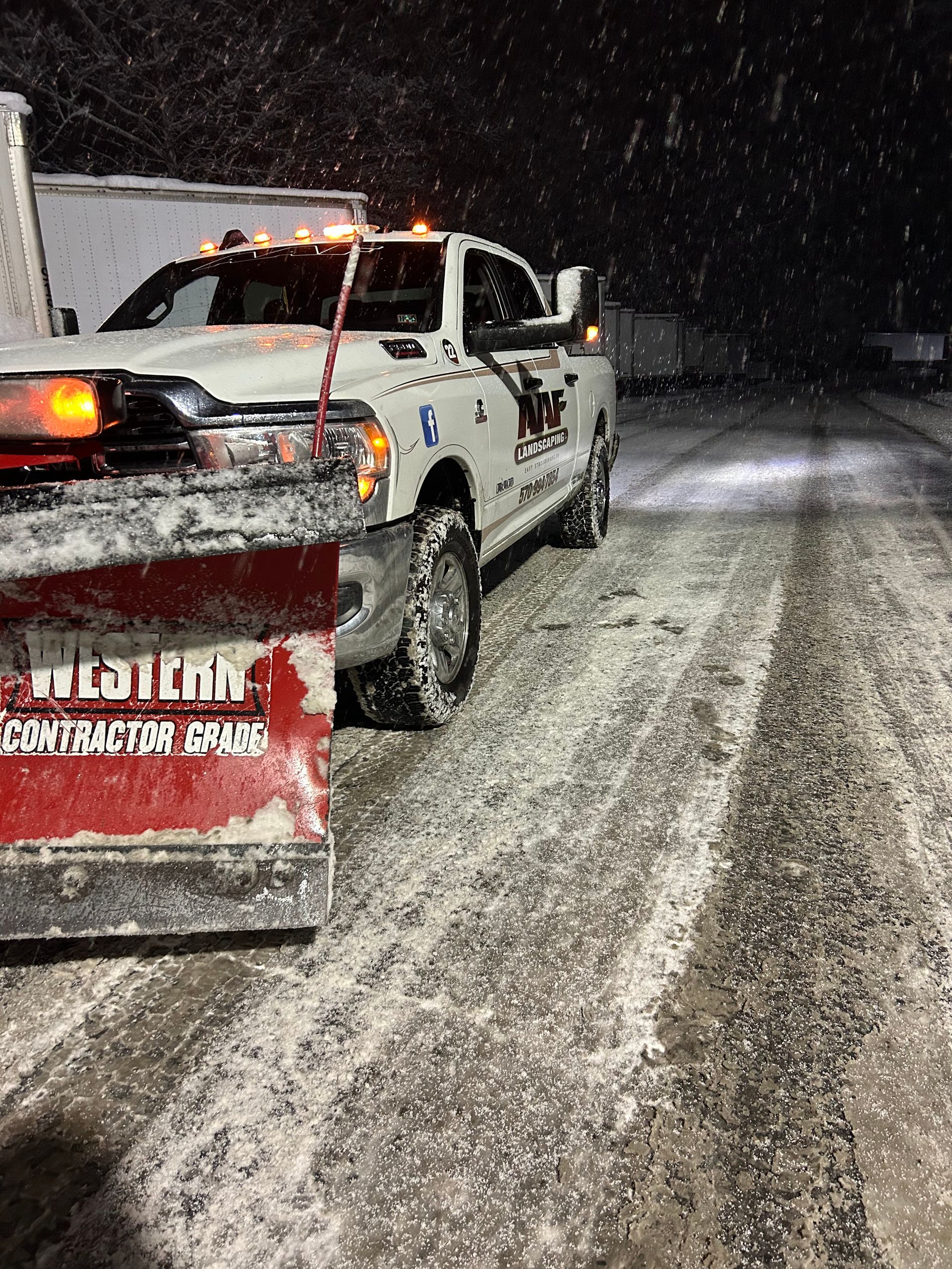 A truck is towing a bulldozer down a snowy road.