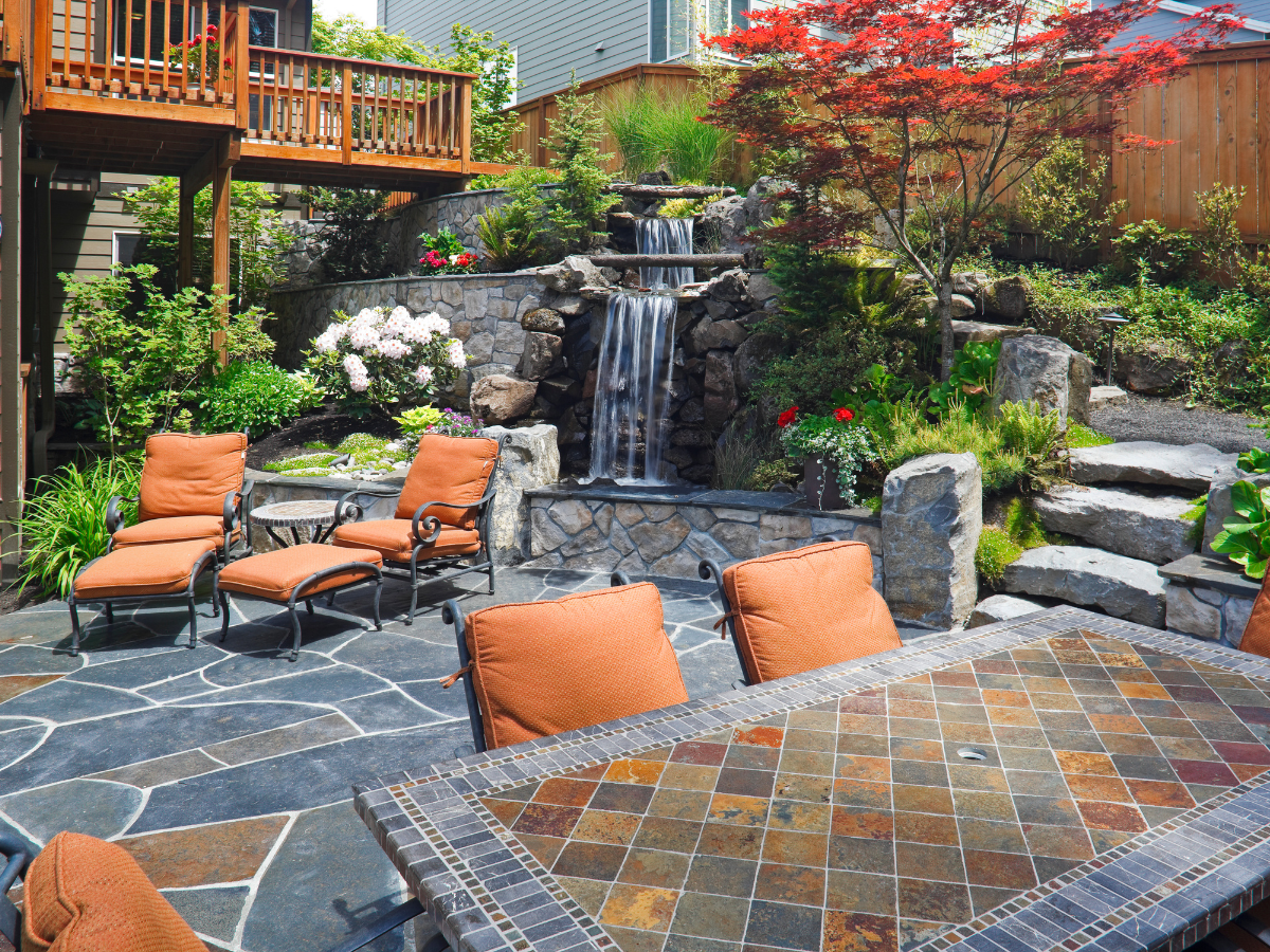 A patio with a table and chairs and a waterfall in the background