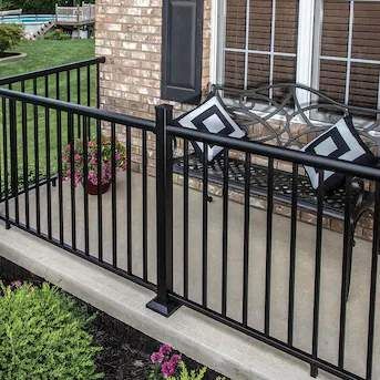 a black railing surrounds a patio with a table and chairs .