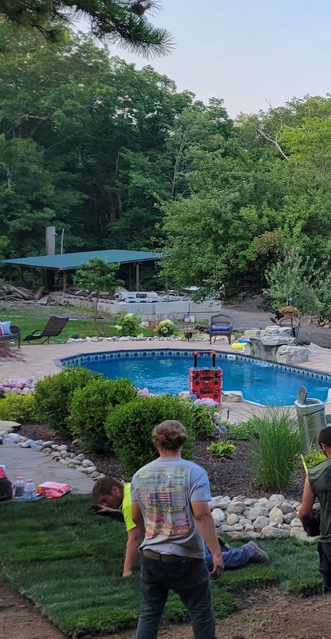 a man is standing in front of a pool in a backyard .