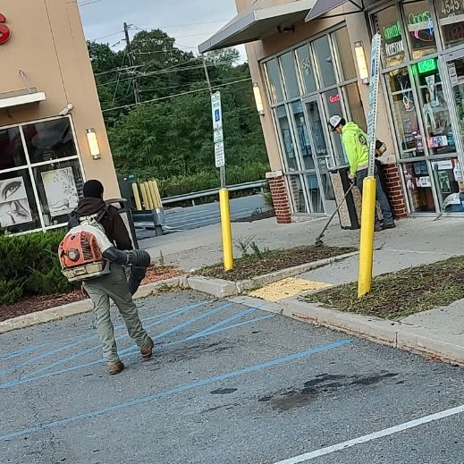 a red and black tractor is parked next to a rock wall .