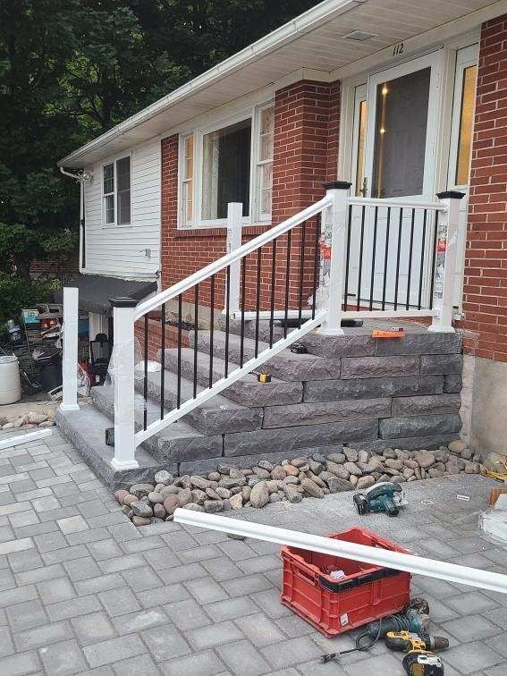 A white railing is being installed on the stairs of a brick house.