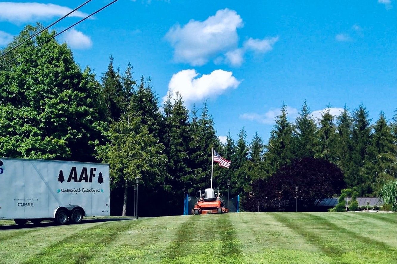 A.A.F Landscaping Trailor and lawn mower on recently cut lawn with American flag in background