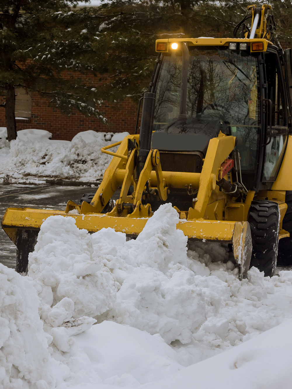 A truck is towing a bulldozer down a snowy road.