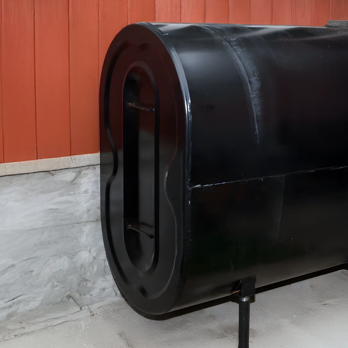 A black barrel is sitting in front of a red wall