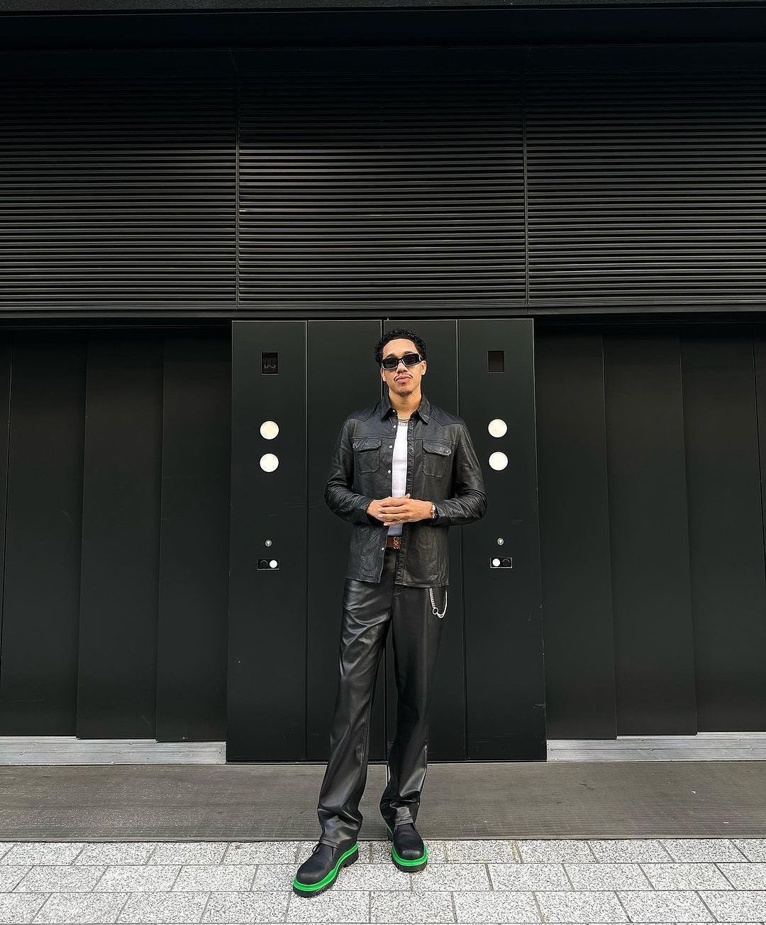 A man in a leather suit is standing in front of a building.