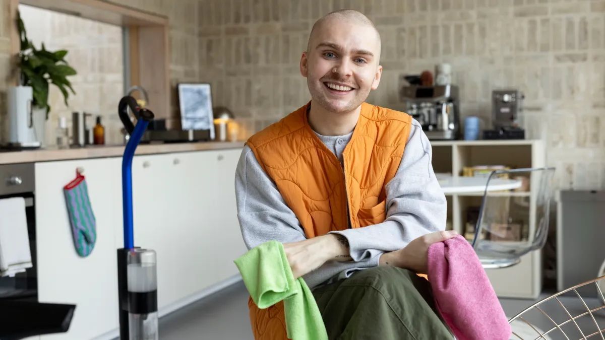 A man in a pink hat is cleaning a counter in a kitchen.