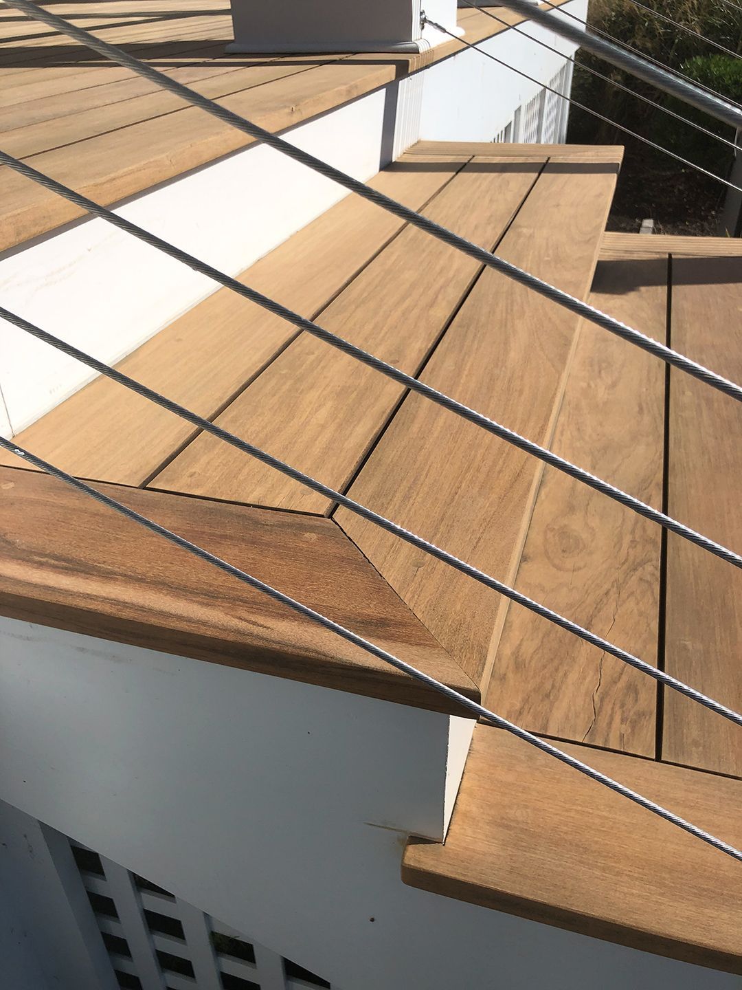 A wooden deck with a stainless steel railing