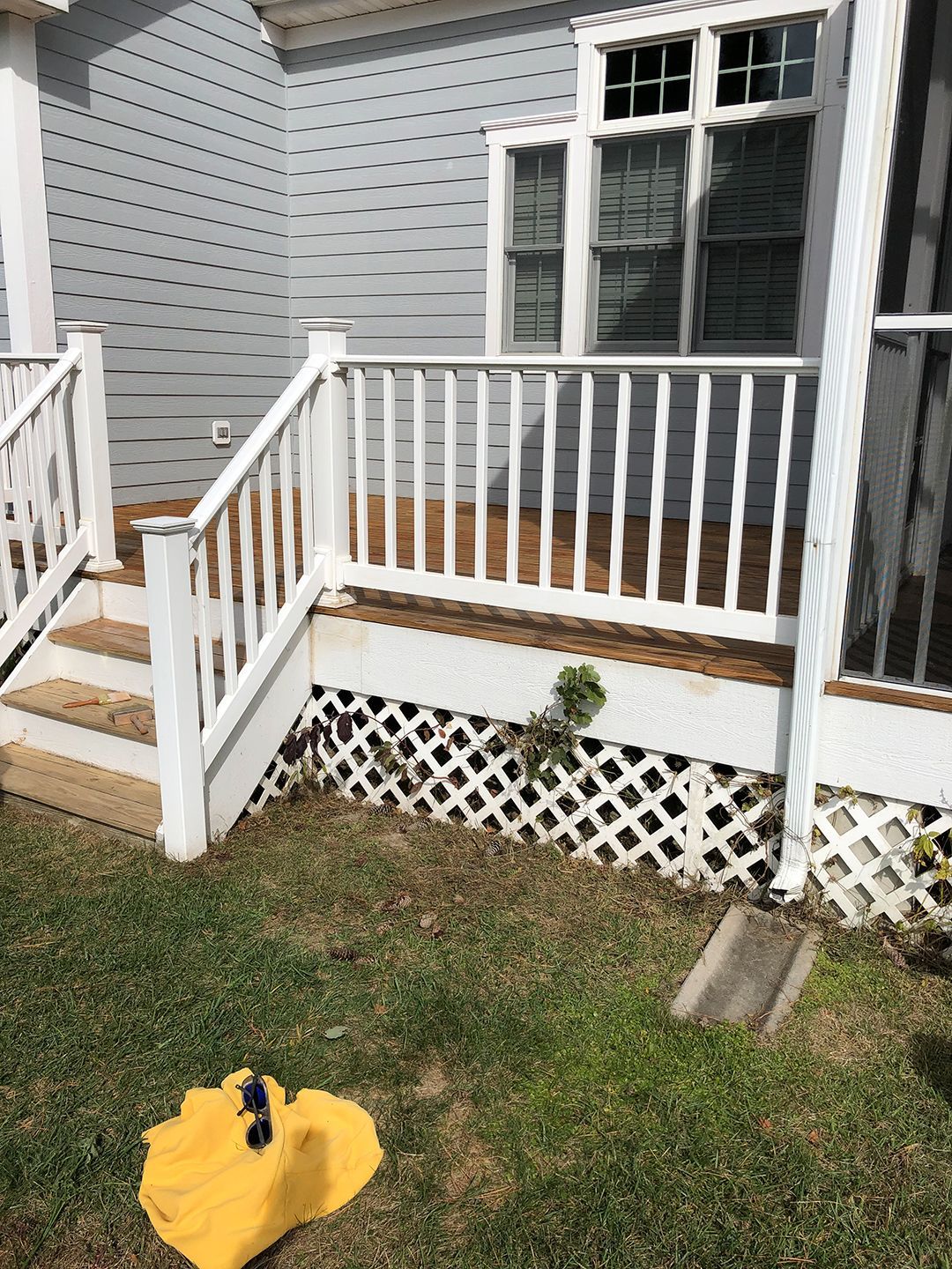 A yellow umbrella is sitting on the grass in front of a house.