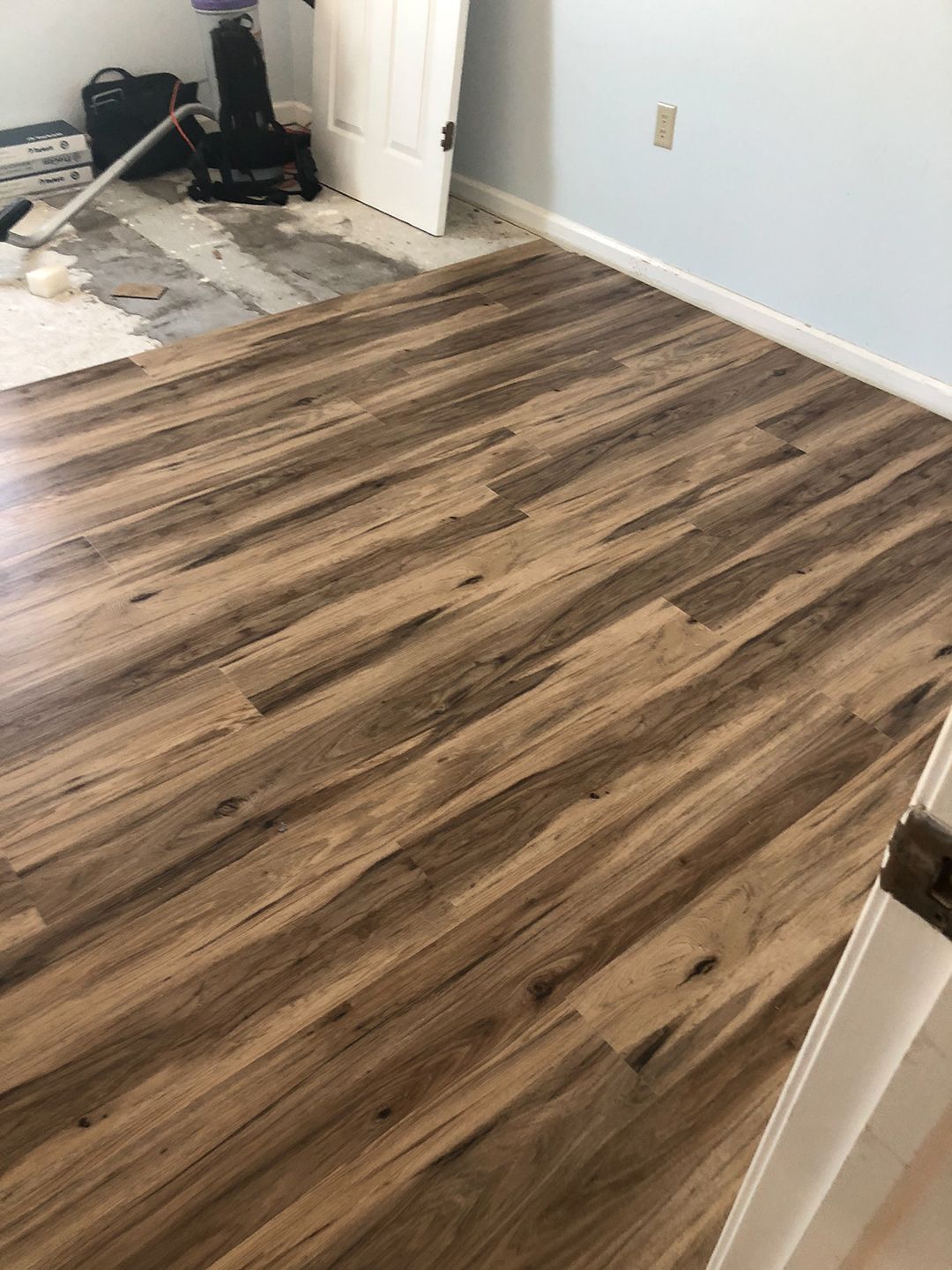 A vacuum cleaner is sitting on a wooden floor in a room.