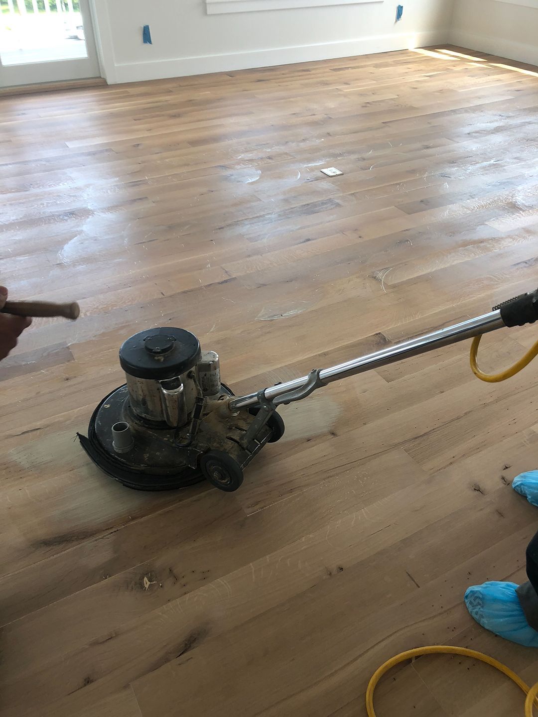 A person is polishing a wooden floor with a machine.
