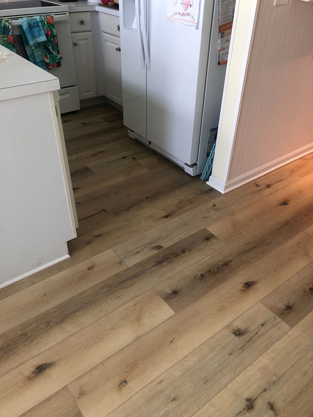 A kitchen with hardwood floors and a refrigerator.