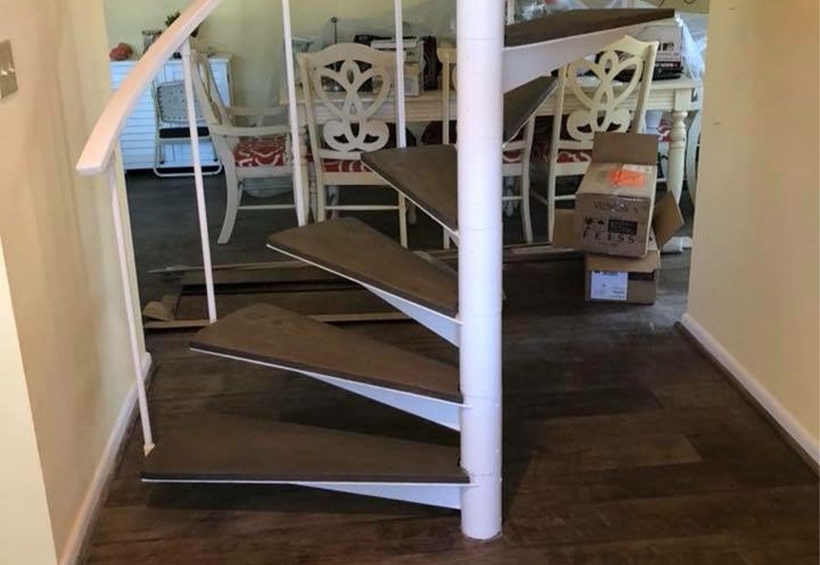 A spiral staircase in a hallway leading to a dining room