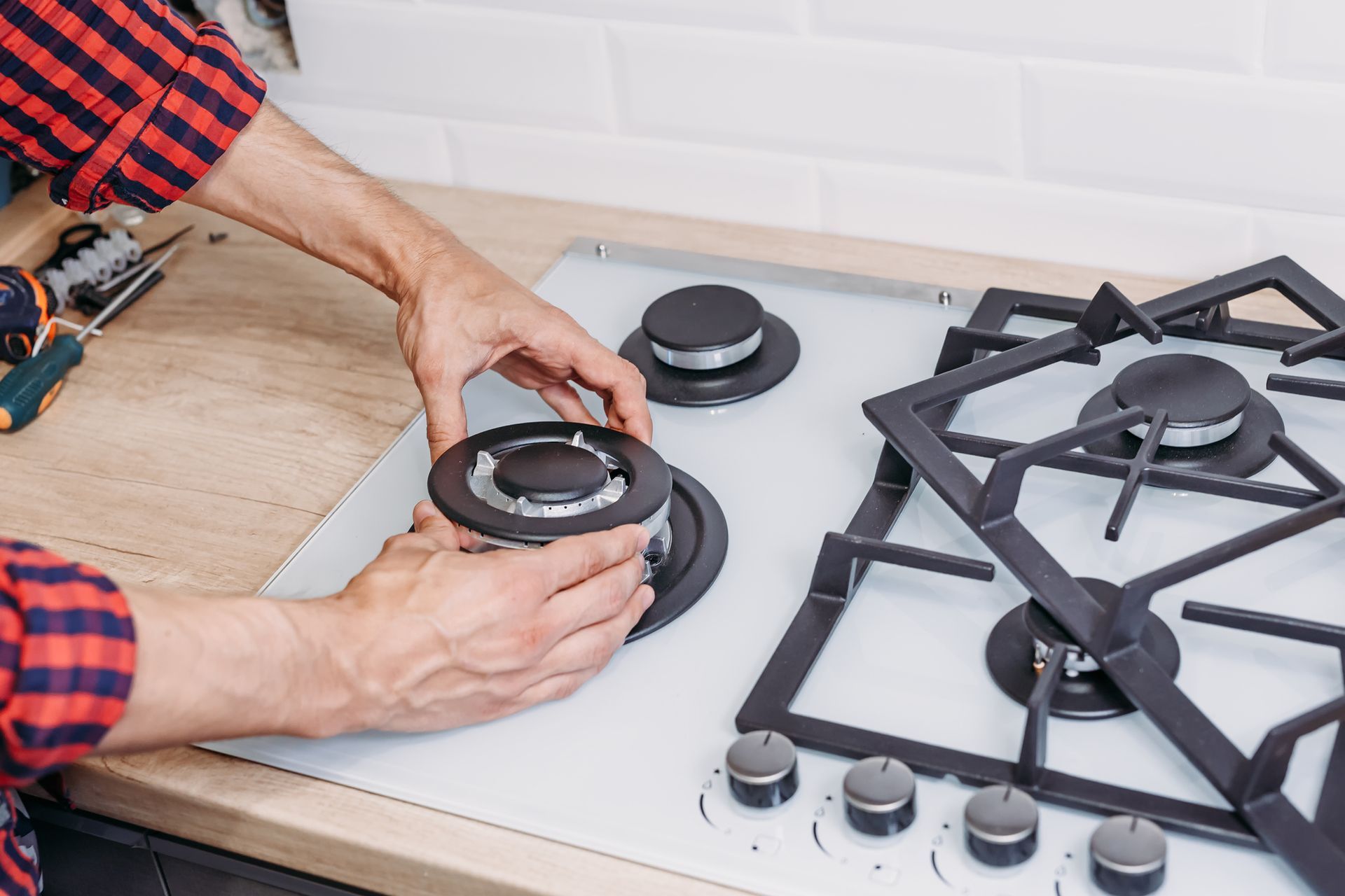 A man is fixing a gas stove in a kitchen.