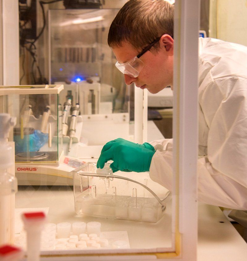 A man wearing green gloves is working in a lab