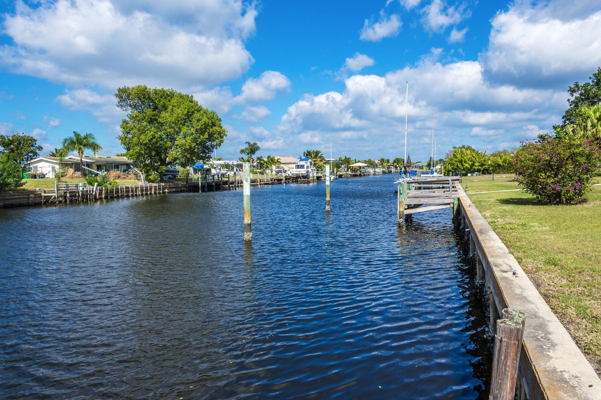 Water canal lined with homes under a bright blue sky with puffy clouds.