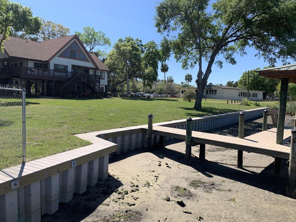Lawn, dock, and house on a sunny day. The dock is attached to a low retaining wall.