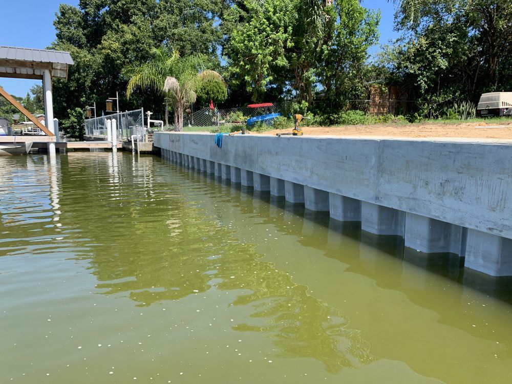 Concrete retaining wall along a waterway; light green water; sunny day.
