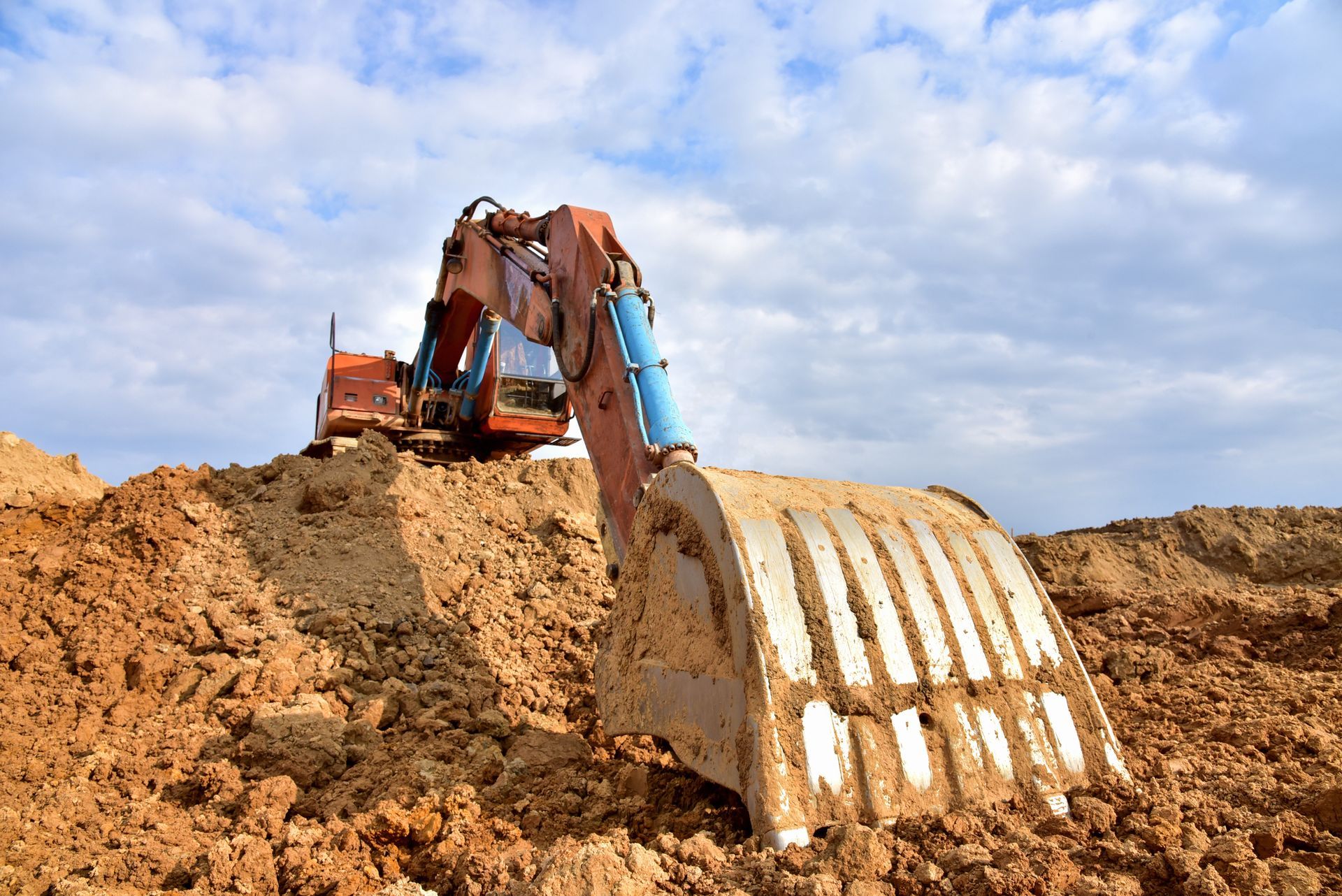A large excavator is digging in a pile of dirt.