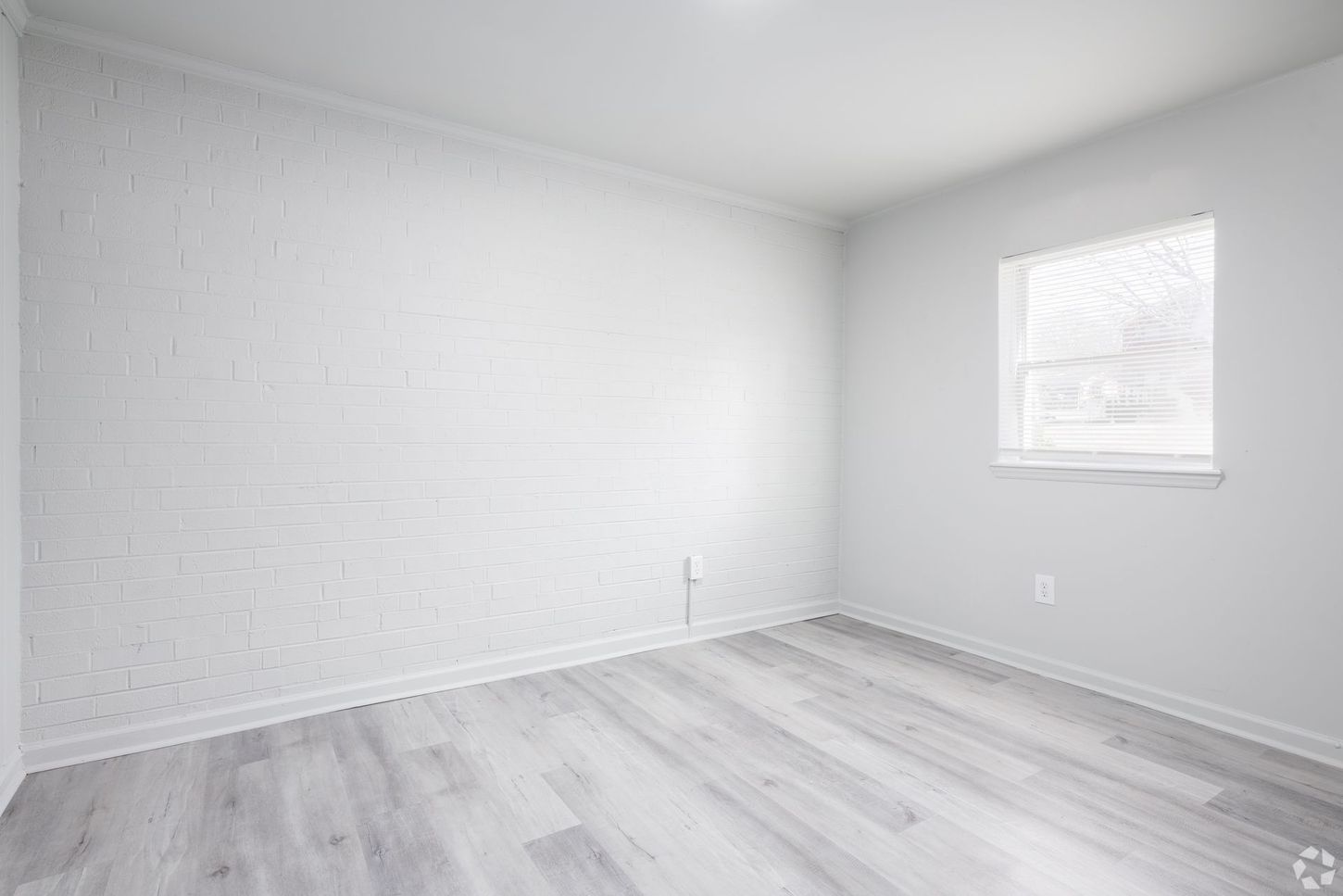 An empty room with a window and hardwood floors.