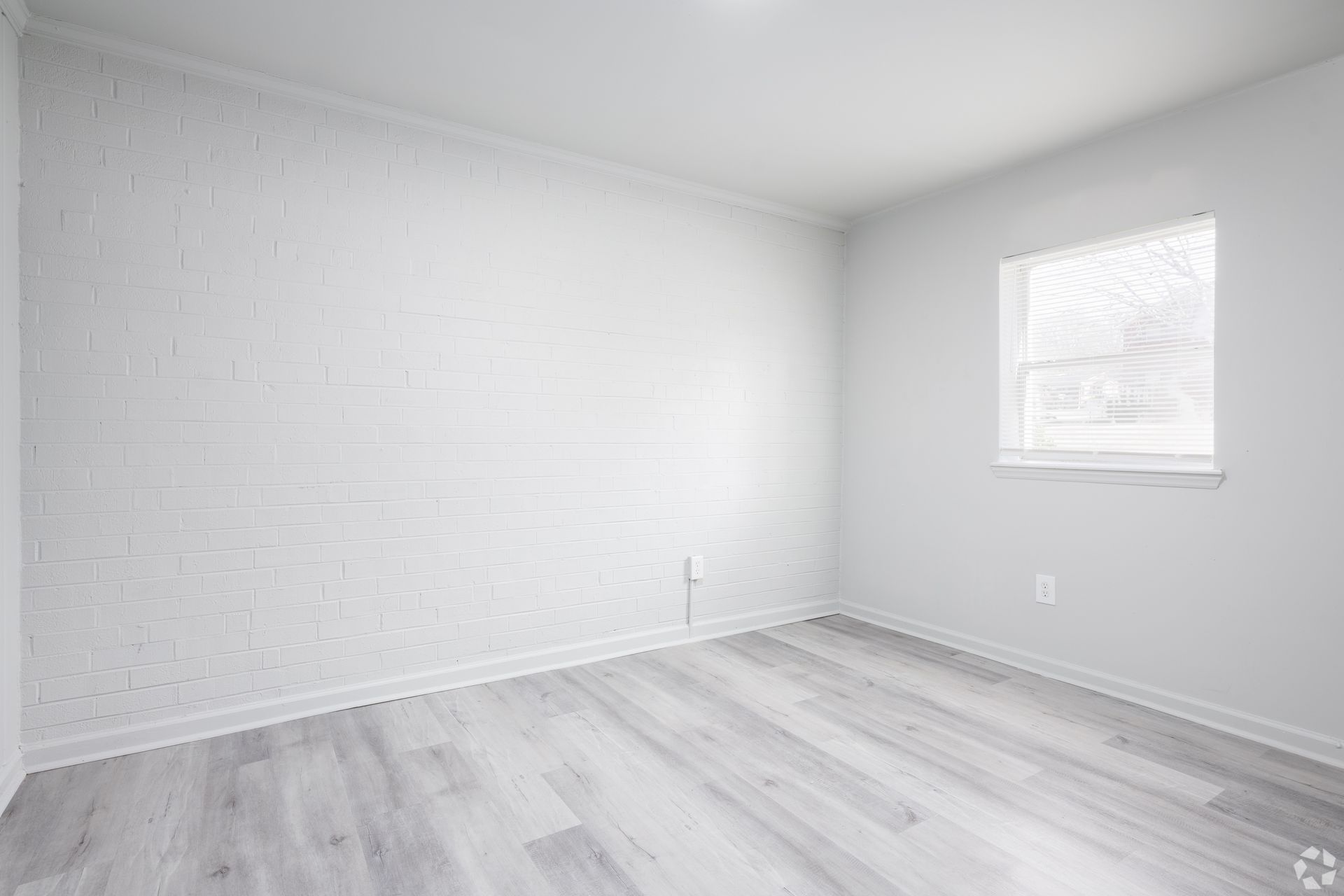 An empty room with a window and hardwood floors.